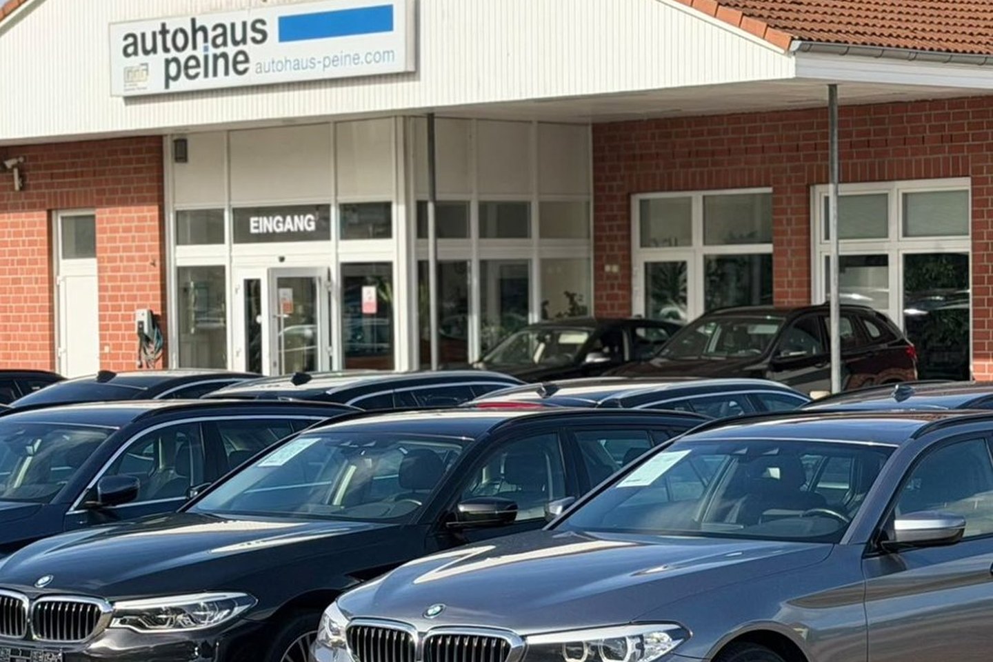 Eingang von Autohaus Peine mit BMW 5er Touring davor